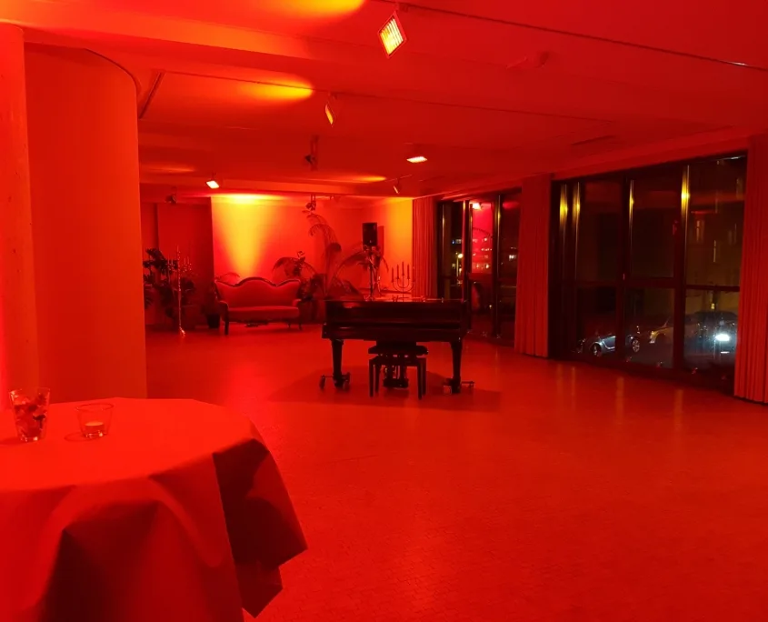Stimmungsvoller Raum der Tangowerkstatt mit rotem Licht, Flügel und Sofa